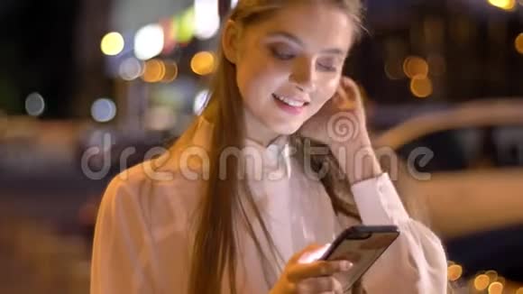 年轻漂亮的恋爱女孩正在夏天晚上在智能手机上输入信息思考概念交流视频的预览图