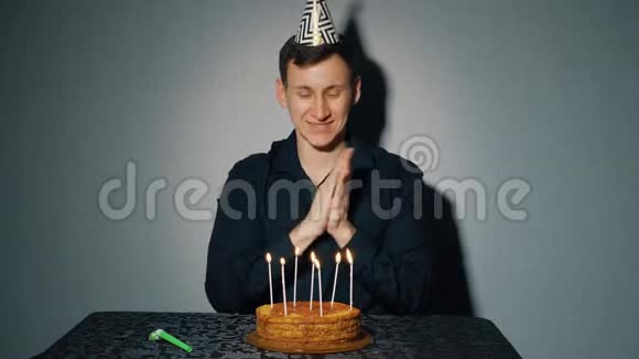 快乐的人庆祝节日他独自坐在一张桌子旁桌上放着一个蛋糕和一支蜡烛视频的预览图