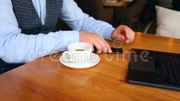 一个年轻人坐在酒吧里用智能手机喝咖啡视频的预览图