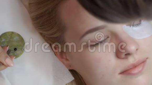 美容师将睫毛延伸至白种人金发女性视频的预览图
