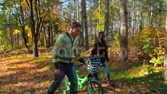 一家人骑着自行车在秋林里散步慢动作视频的预览图
