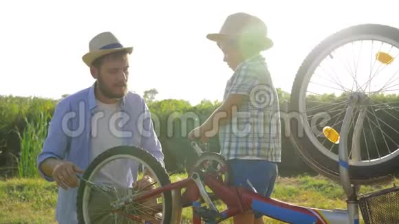 父亲和儿子在一个家庭周末的背景下在背光下修理自行车视频的预览图