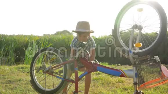 好奇的小男孩在乡村背景下背着背光旋转自行车和脚踏车视频的预览图
