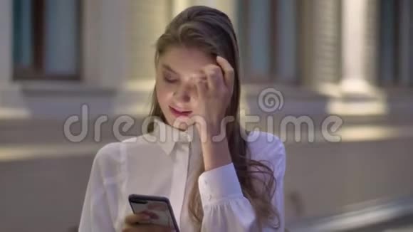 年轻迷人的女孩在夏天的晚上在智能手机上输入信息思考观念交流视频的预览图