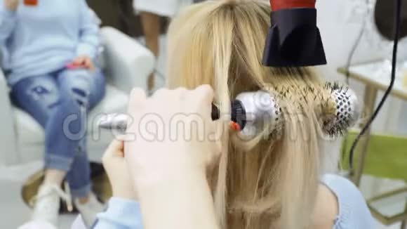 理发师用吹风机和刷子擦干女性头发视频的预览图