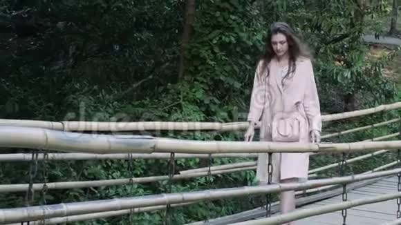 小女孩沿着公园里一座真正的竹桥散步视频的预览图