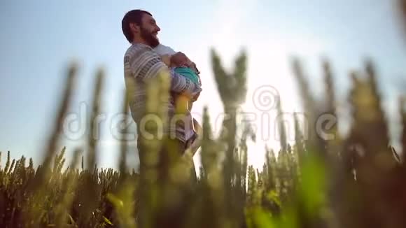 坚强的父亲在天空中游说儿子日落时分在麦田里和他玩视频的预览图
