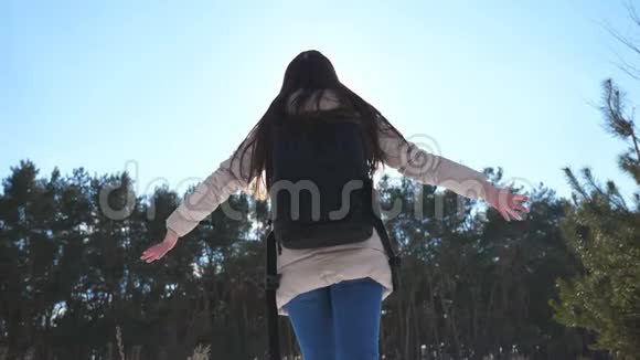 年轻女孩带着背包跳跃在背景下与冬天的森林一起快乐女人举手享受自由视频的预览图