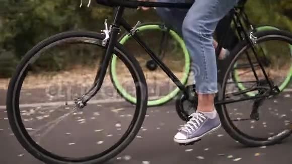 秋日清晨一对夫妇骑着自行车在当地公园的沥青路上骑着自行车把腿蹬起来视频的预览图