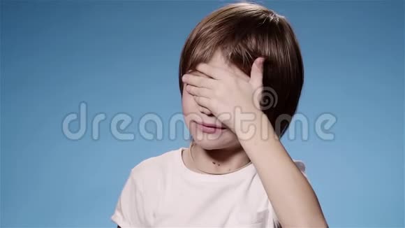 超级慢动作小男孩揉眼睛哭或累蓝色背景视频的预览图