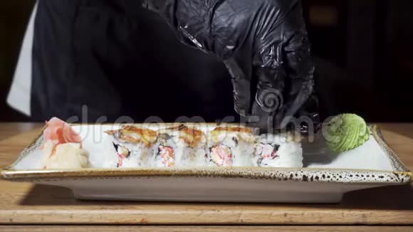 日本料理店的厨师用手把寿司上的食材放在盘子里上面放着芥末和生姜视频的预览图