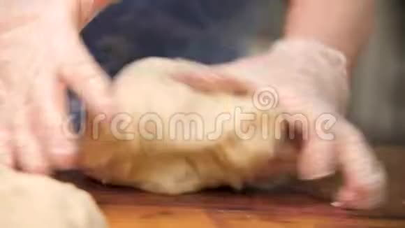女人在烹饪手套上揉面在木板上食物准备的概念库存录像双手合拢视频的预览图