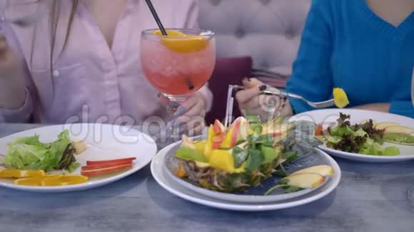 美味的饮食年轻女性在午餐时与水果和蔬菜交流在咖啡馆喝新鲜果汁视频的预览图