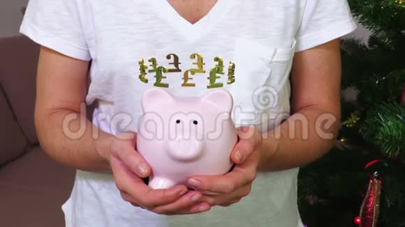 女子持有粉红储蓄罐英国磅标志概念视频的预览图