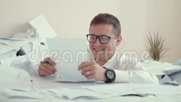 办公室里一个年轻人坐在一堆文件里在文件上签名3这位上班族正在大量的食物中溺死视频的预览图