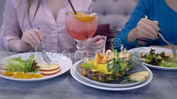 女人节食女朋友午餐时与水果和蔬菜交流喝新鲜果汁坐在餐桌旁视频的预览图