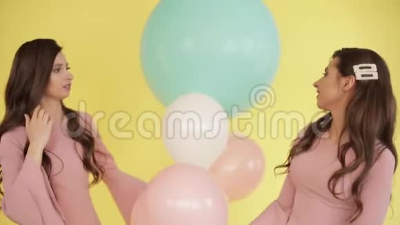 穿着粉色裙子玩彩色气球的漂亮双胞胎视频的预览图