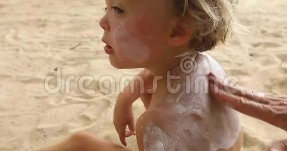 妈妈在沙滩上给儿子涂防晒霜视频的预览图
