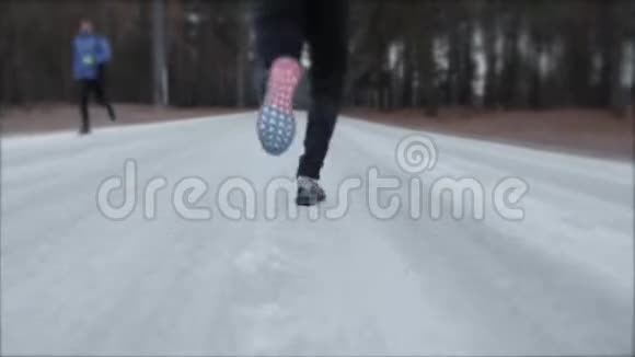 白种人年长的女人在下雪的冬季公园跑步前先戴上耳机近距离射击视频的预览图
