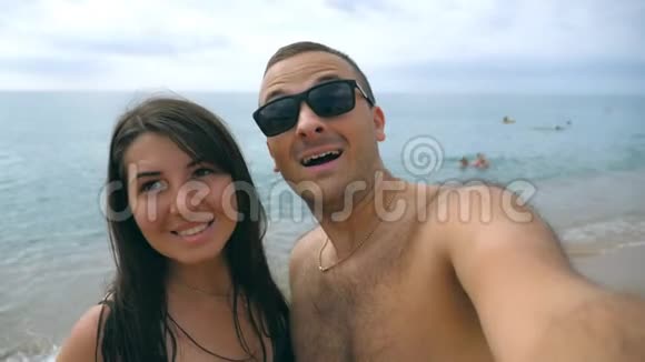 年轻的幸福夫妇在海边拍自我肖像微笑的一对在海边自拍性格开朗的人视频的预览图