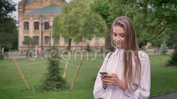 年轻漂亮的女孩在夏天在智能手机上输入信息调情概念交流概念视频的预览图