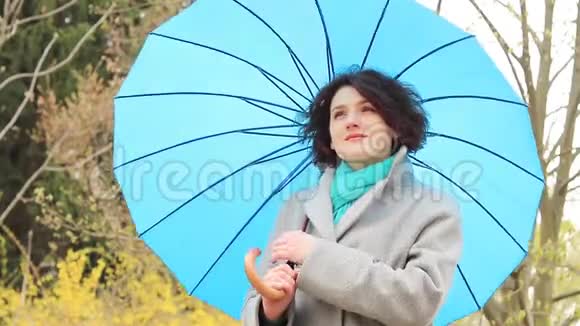 带着蓝色伞的年轻红头发女人视频的预览图