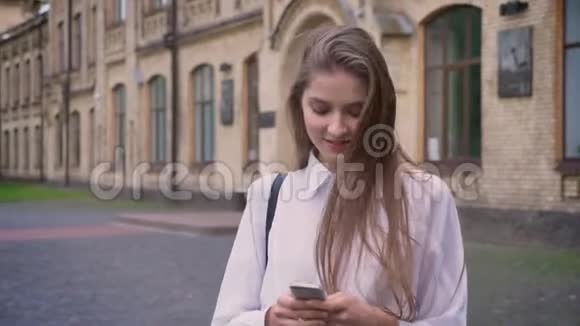 年轻漂亮的女孩在夏天在智能手机上阅读信息交流理念视频的预览图