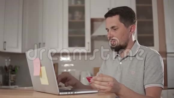 成年男子在网上支付费用用笔记本电脑把卡片的数据放到网上视频的预览图