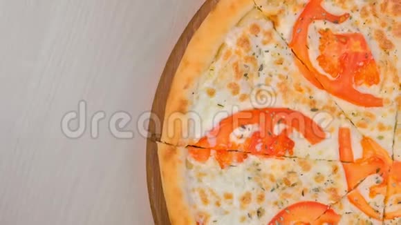 在木板上用西红柿和奶酪切片披萨的一半上景视频的预览图