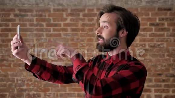 年轻有魅力的留着胡子的男人在智能手机上用视频聊天积分认可签名交流等概念视频的预览图
