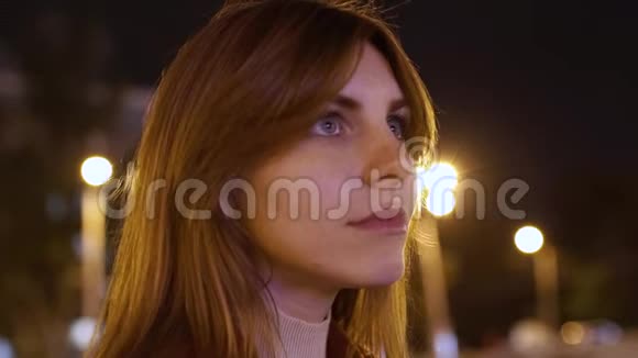 一个年轻的红发迷人的女人在户外夜晚的特写广告招牌上的闪光灯视频的预览图