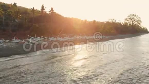 在温暖的日落或日出时带着渔船的海洋和海滩空中景观视频的预览图