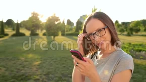 微笑迷人的女孩在她的智能手机上与朋友浏览阅读新闻阳光明媚的阳光视频的预览图