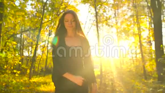美丽的女孩穿着黑色的衣服在秋天的森林里散步享受着好天气视频的预览图