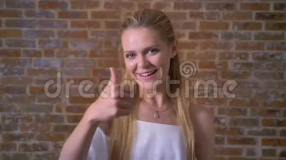 年轻可爱的金发女孩像标志微笑砖墙在背景上视频的预览图