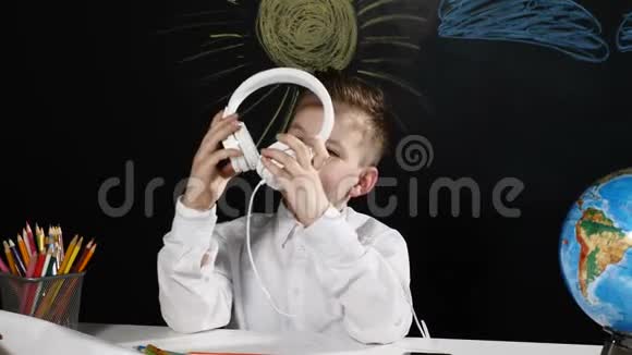 学校观念可爱的男孩坐在一张桌子上桌子上有地球仪后面有一块黑板无聊的男生视频的预览图