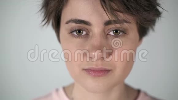 一位短发眨着眼睛半笑着的年轻女子的肖像视频的预览图