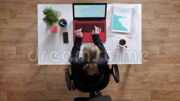 年轻女性扎着马尾辫在笔记本电脑上打字坐在办公桌后面拿着咖啡文件视频的预览图