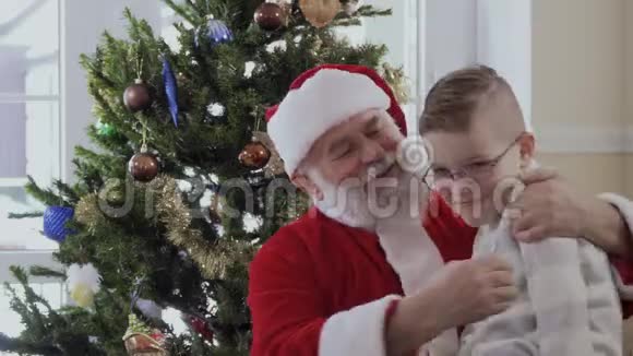 圣诞老人拥抱并挤压着杉树附近的男孩视频的预览图