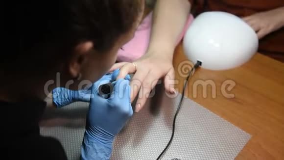 戴白色手套的摩尼教医生用无色清漆覆盖女性指甲视频的预览图