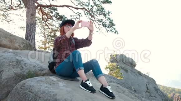 山顶上的女孩女游客在手机上用日出拍照视频的预览图
