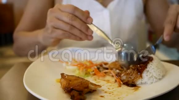 年轻的亚洲女人吃白色盘子里的鸡肉视频的预览图
