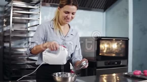 美丽微笑的白种人女人糕点厨师在现代时尚的厨房工作用钢碗搅拌原料视频的预览图