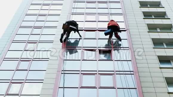 两个工业登山者正在清洗一座现代化办公楼的门面视频的预览图