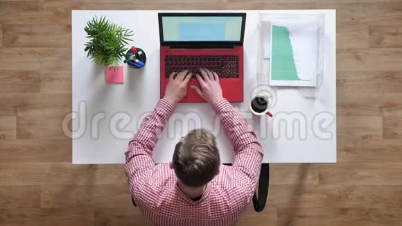 戴眼镜的年轻人在手提电脑上工作女人给他文件顶头坐在桌子后面视频的预览图