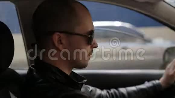 戴太阳镜的年轻人在高速公路上开车戴墨镜的人在城里开车视频的预览图