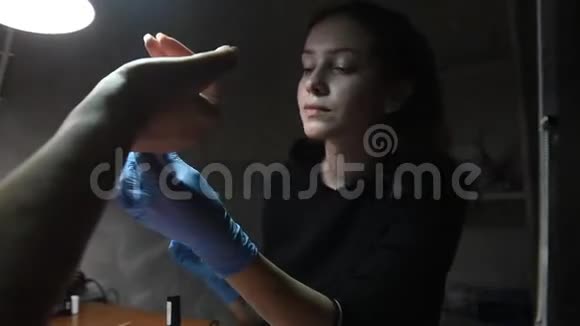 戴白色手套的摩尼教医生用无色清漆覆盖女性指甲视频的预览图