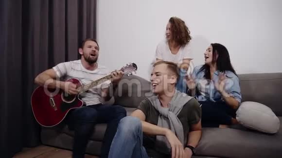 快乐的朋友坐在沙发上听Guy弹声吉他一起玩得开心视频的预览图