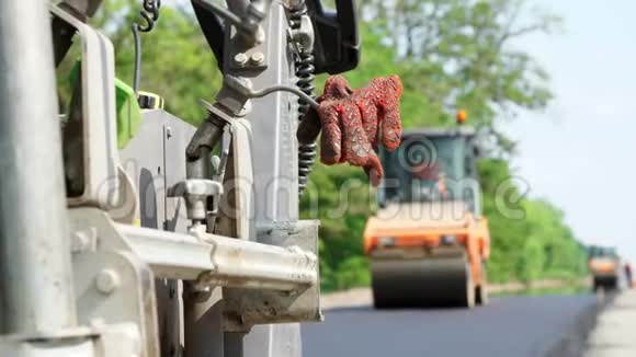 修公路道路建设工程在前景中在铺设沥青的机器上工人留下了特殊的橙色视频的预览图