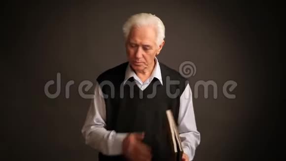老人拿着书和手机摆姿势视频的预览图